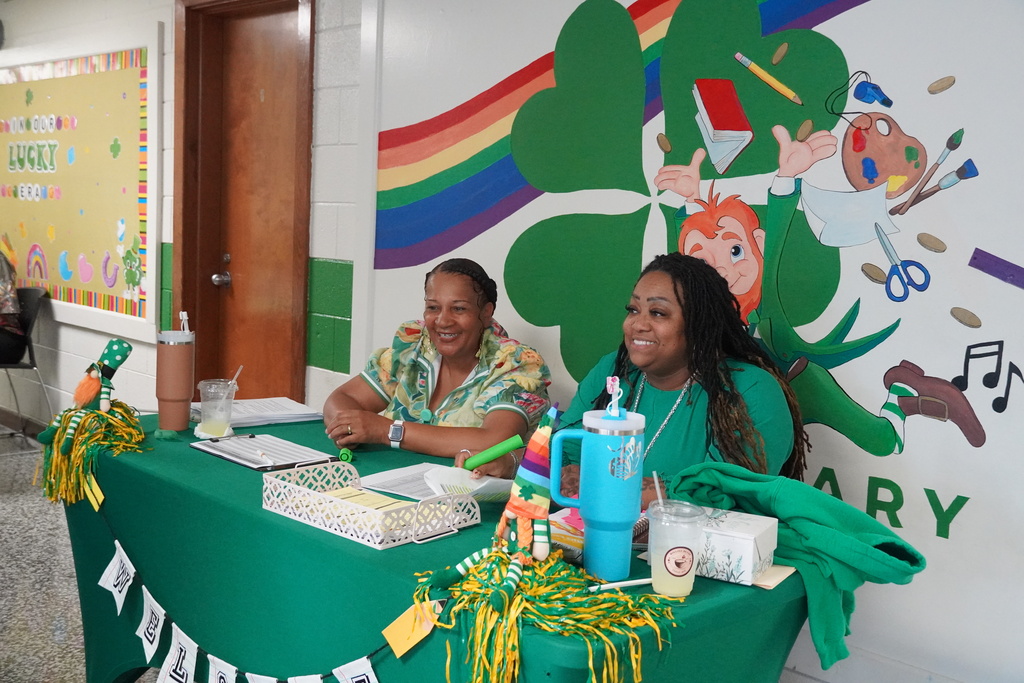 Dublin Primary School staff members are sitting behind a green table smiling. 