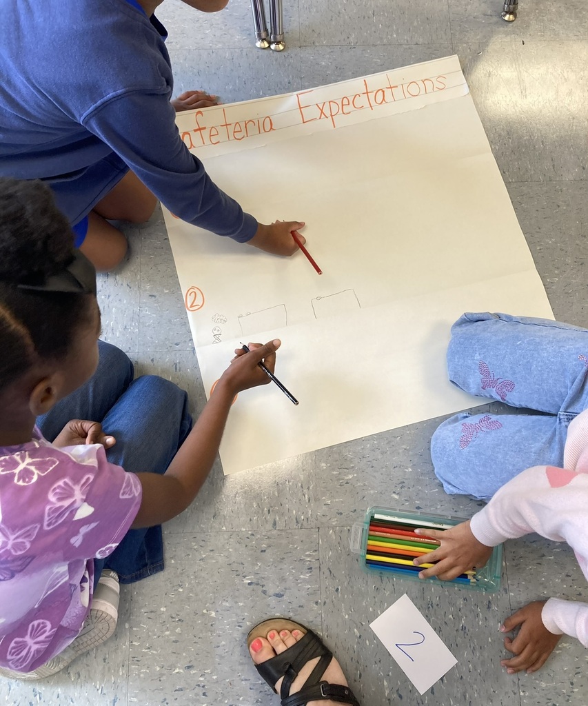 Students collaborate on a poster while reviewing classroom expectations.