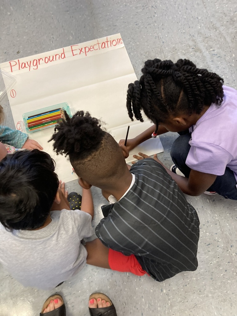 Second graders work together to create a poster about classroom expectations.