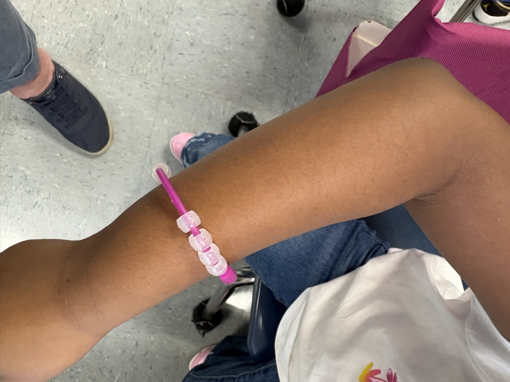 Student proudly holds up a colorful magic bead bracelet.