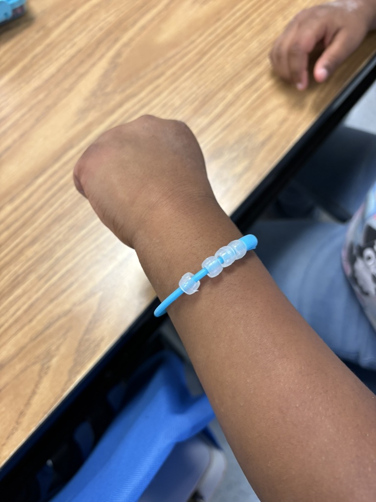 Student shows a blue bracelet with beads changing color in sunlight.