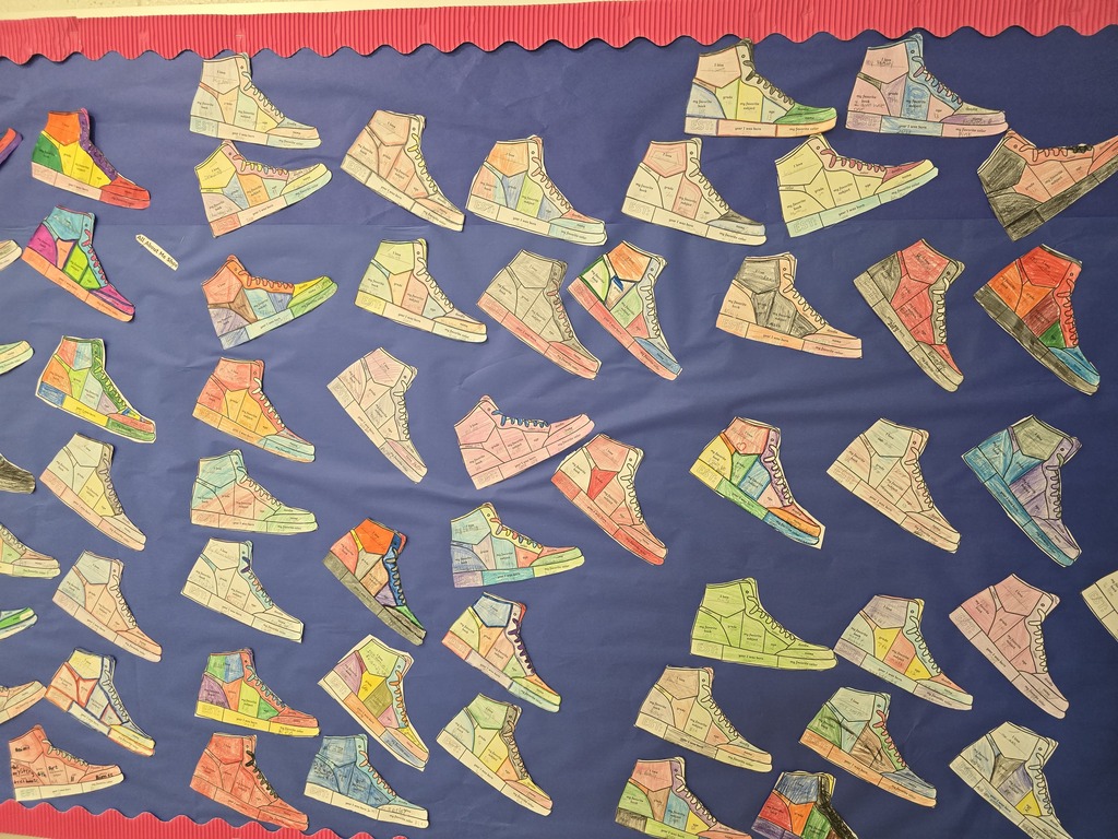 Alt text: A colorful bulletin board displays dozens of student-created “All About Me” sneaker designs. Each paper sneaker is uniquely colored and filled with personal details, showcasing students’ creativity, interests, and individuality.