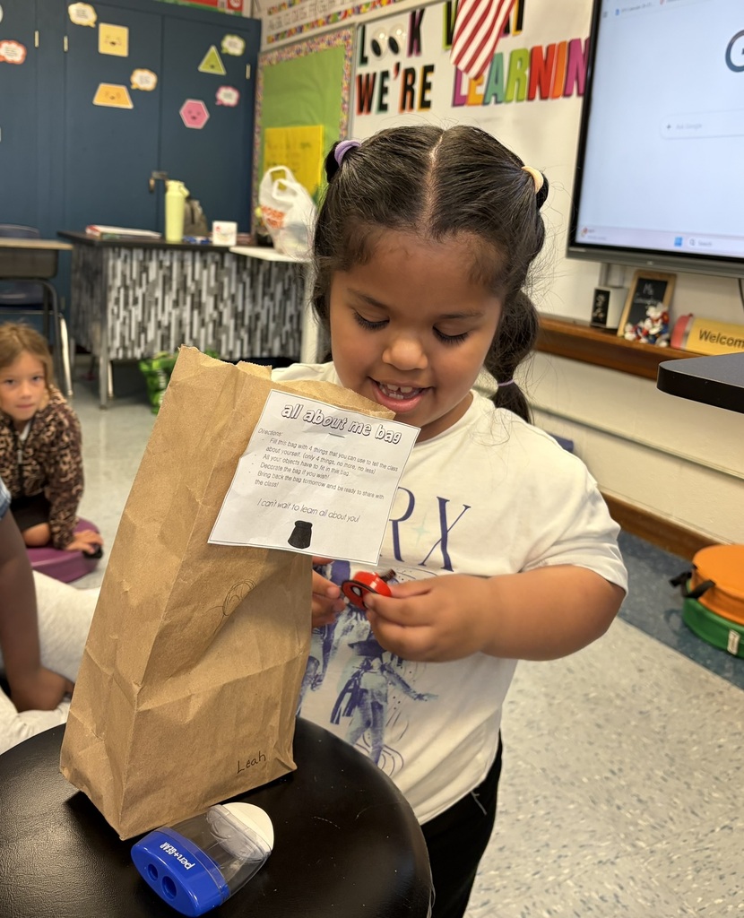Student smiles while sharing an item from her “All About Me” bag with the class.
