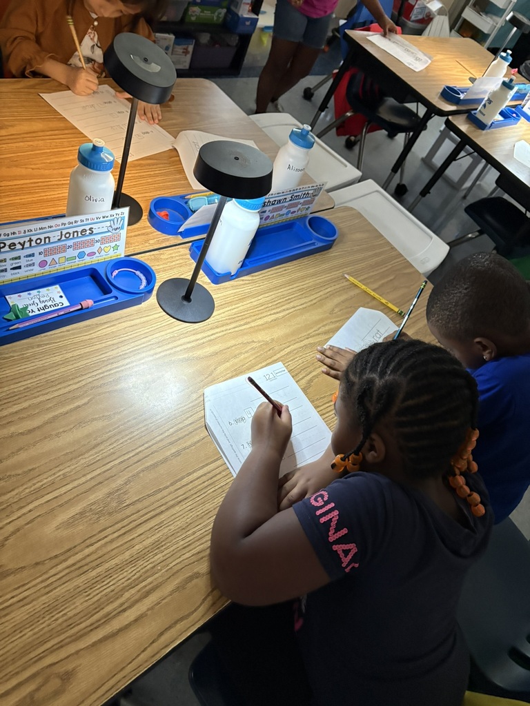 Student works on a phonics worksheet beside a table lamp and classroom supplies.