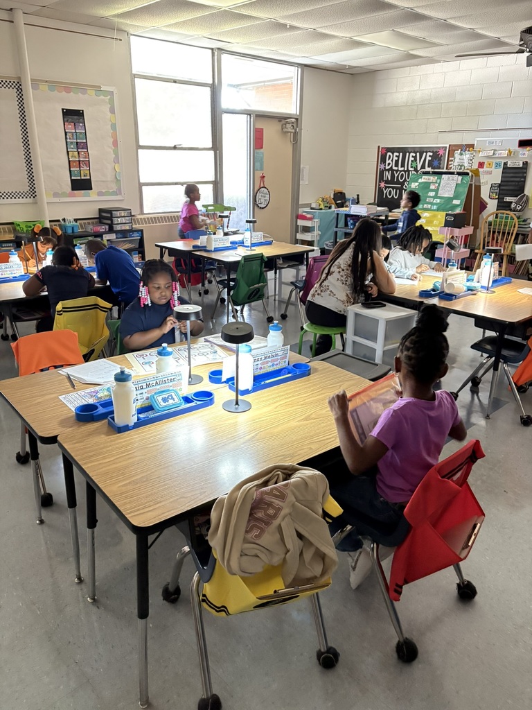 Students work at classroom tables using small lamps instead of overhead lighting.