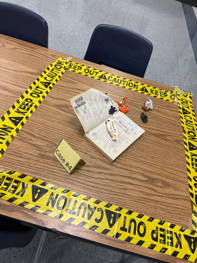 Damaged library book and candy wrappers displayed as evidence in a taped-off case area.