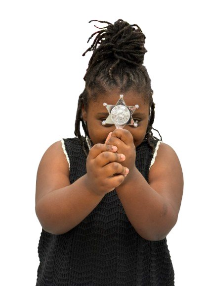 Young girl holding a silver sheriff’s badge toward the camera.
