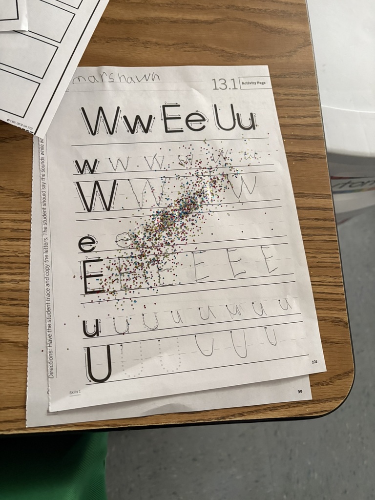 Handwriting practice sheet featuring W, E, and U letters covered with colorful fairy dust.