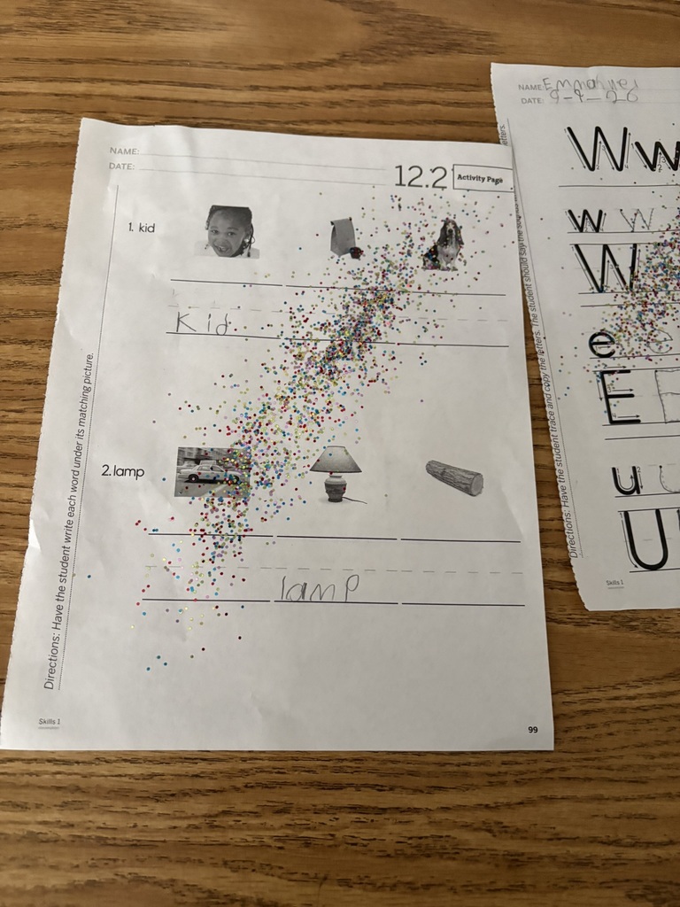 Handwriting worksheet with “kid” and “lamp” written neatly and colorful fairy dust scattered over the work.