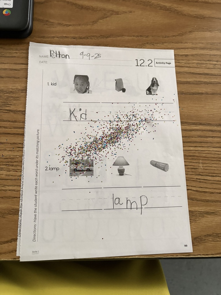 Student handwriting worksheet with “kid” and “lamp” completed and colorful fairy dust sprinkled across the page.