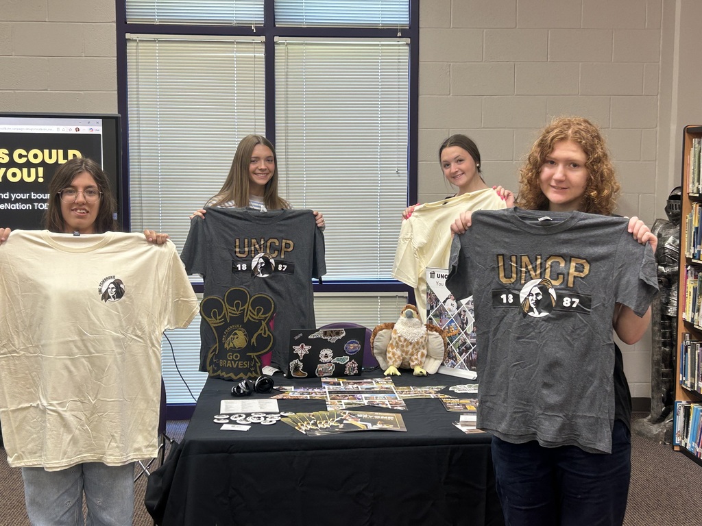 Four seniors hold up UNCP T-shirts they received during the UNC Pembroke admissions visit.