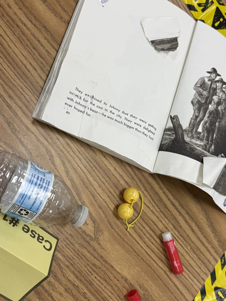 Close-up of a damaged library book surrounded by clues, including a water bottle and glue stick.