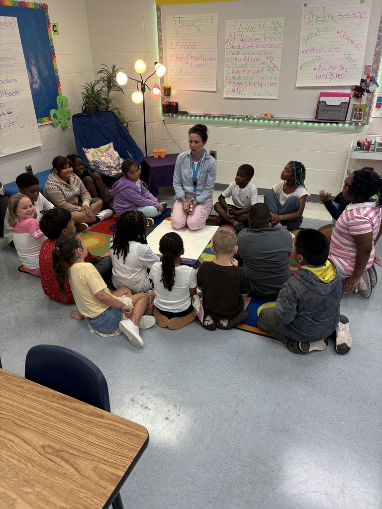 Students sit in a circle talking with their teacher.
