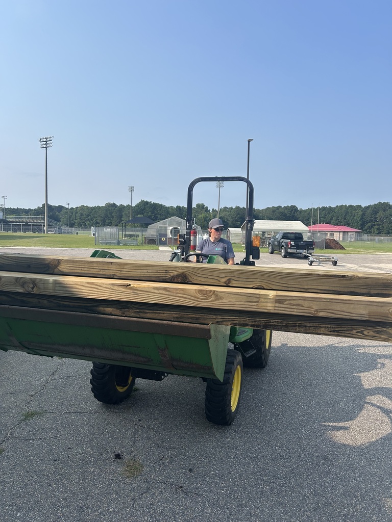 A woman driving a green tractor.