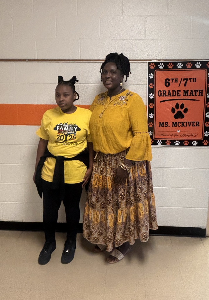 Student and teacher smiling in hallway.