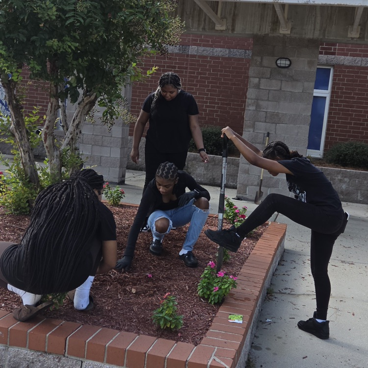 tissue squad in a garden bed by one student uses a shovel