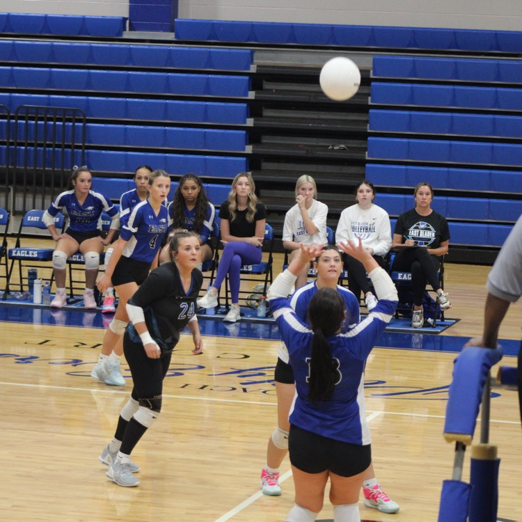 girls and blue jerseys black shorts playing volleyball