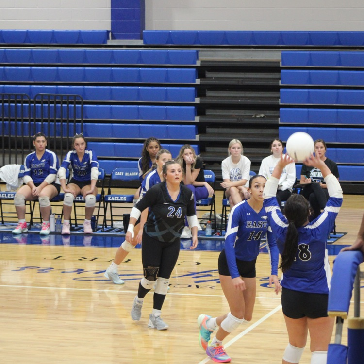 girls and blue jerseys black shorts playing volleyball