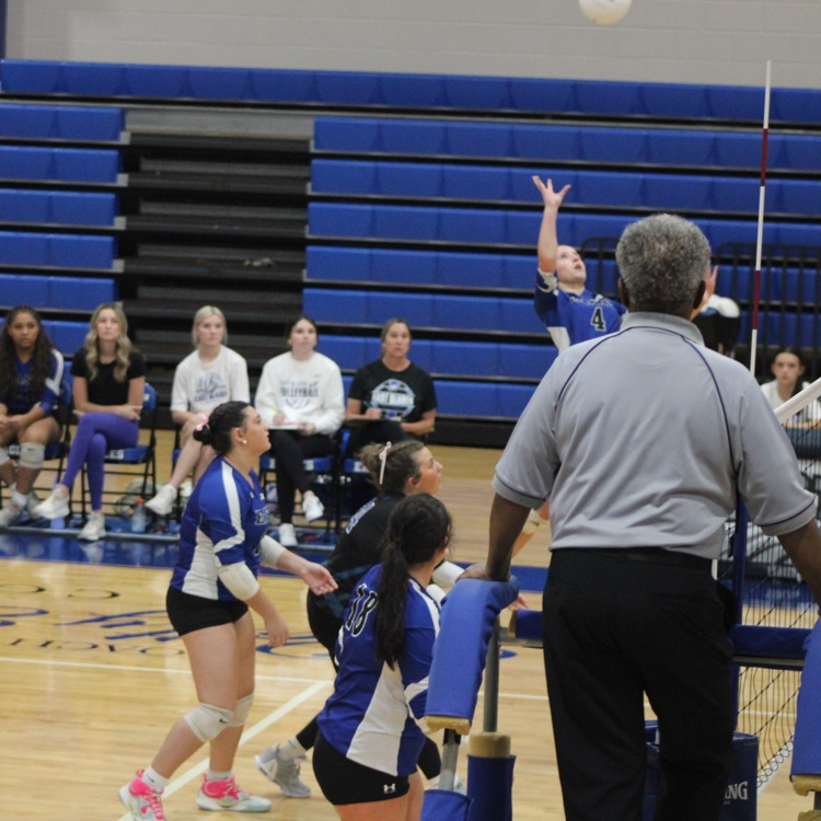 girls and blue jerseys black shorts playing volleyball