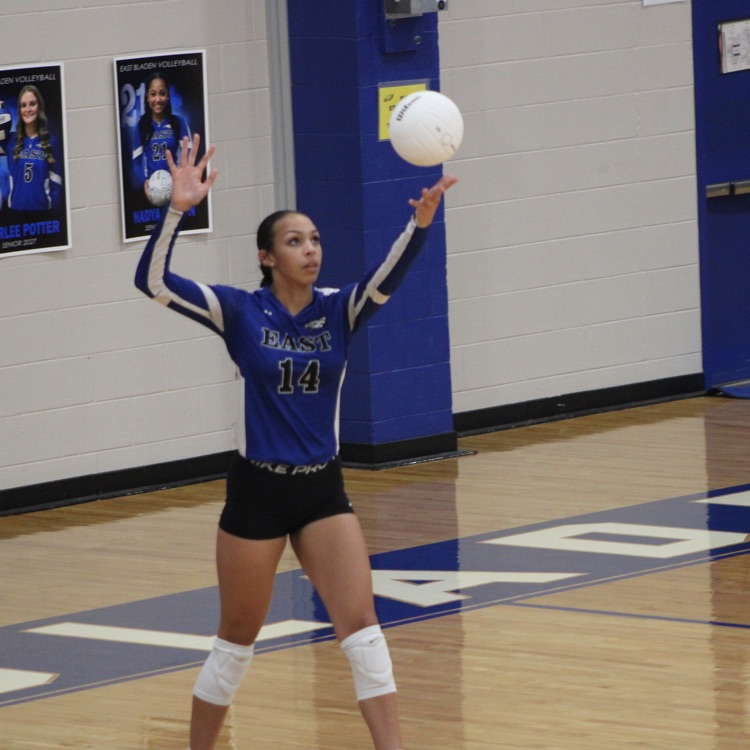 girls and blue jerseys black shorts playing volleyball