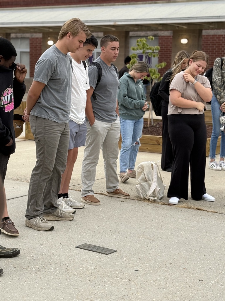 Students stand together outside West Bladen High School with heads bowed during See You at the Pole prayer.