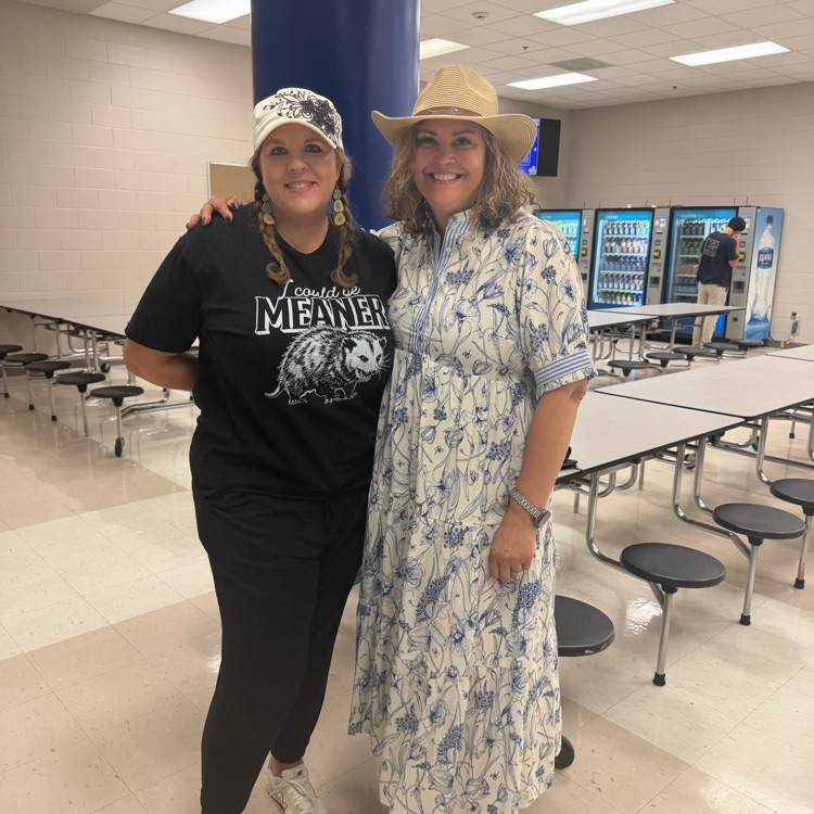 lady in flowery dress and lady in all black wearing hats 