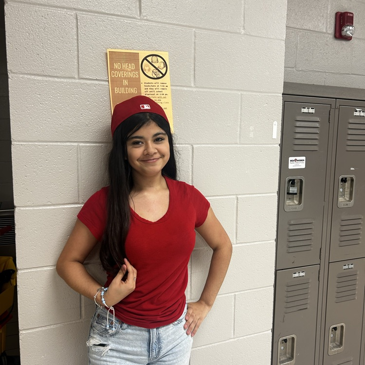 girl in red shirt wearing a hat by an orange no hat sign