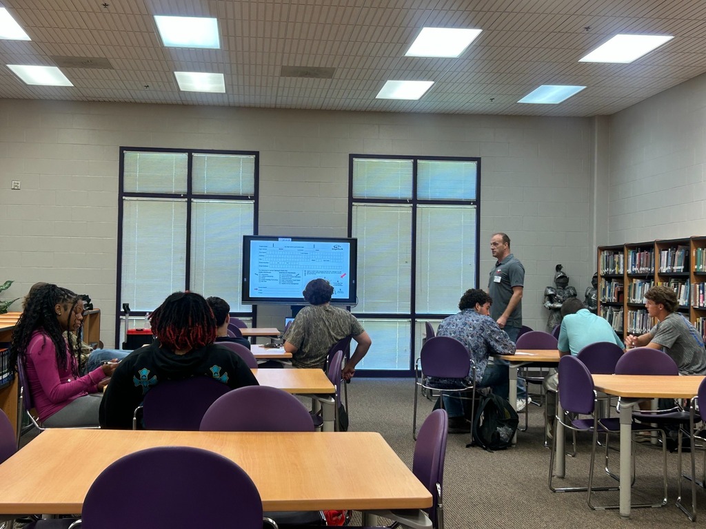A WyoTech representative speaks to students during the information session while a presentation slide is displayed on the screen.