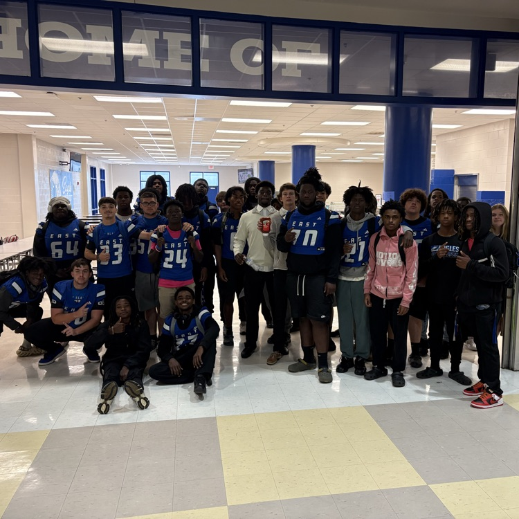A group of football players posing in front of the cafeteria