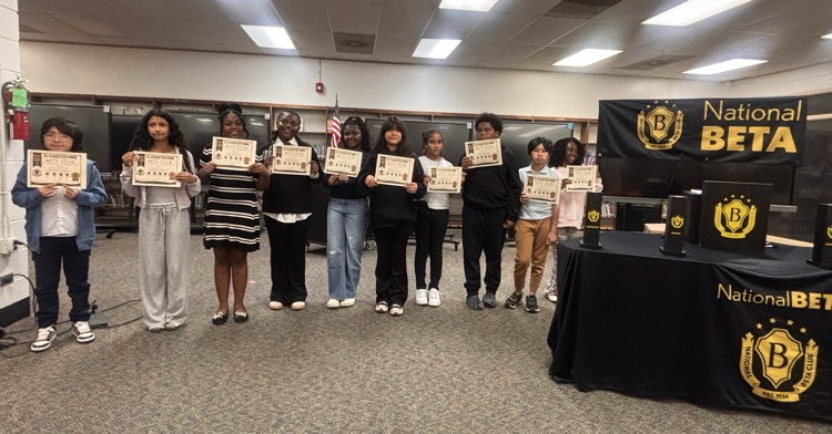 students standing in front of audience holding certificates 