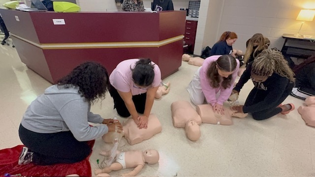 Students practice CPR and bag valve mask ventilation on a training mannequin