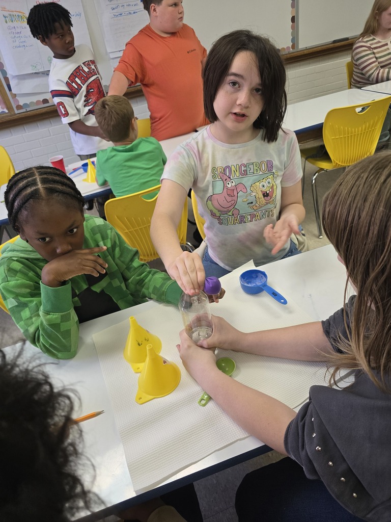 Bladenboro Middle School fifth graders collaborate during a hands-on chemical reaction lab. Students carefully position a purple balloon over a bottle while classmates observe and assist. The activity encourages teamwork, scientific inquiry, and understanding how chemical reactions can produce gas.