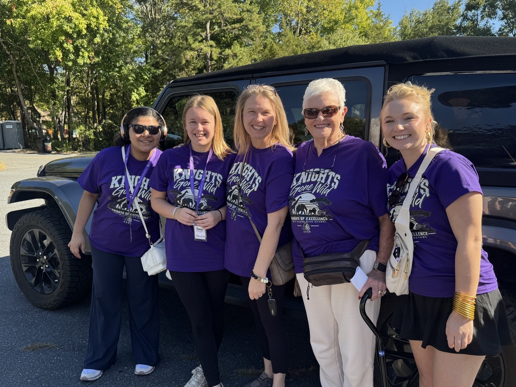 five females in purple shirts posing before they set out on an adventure at the NC zoo