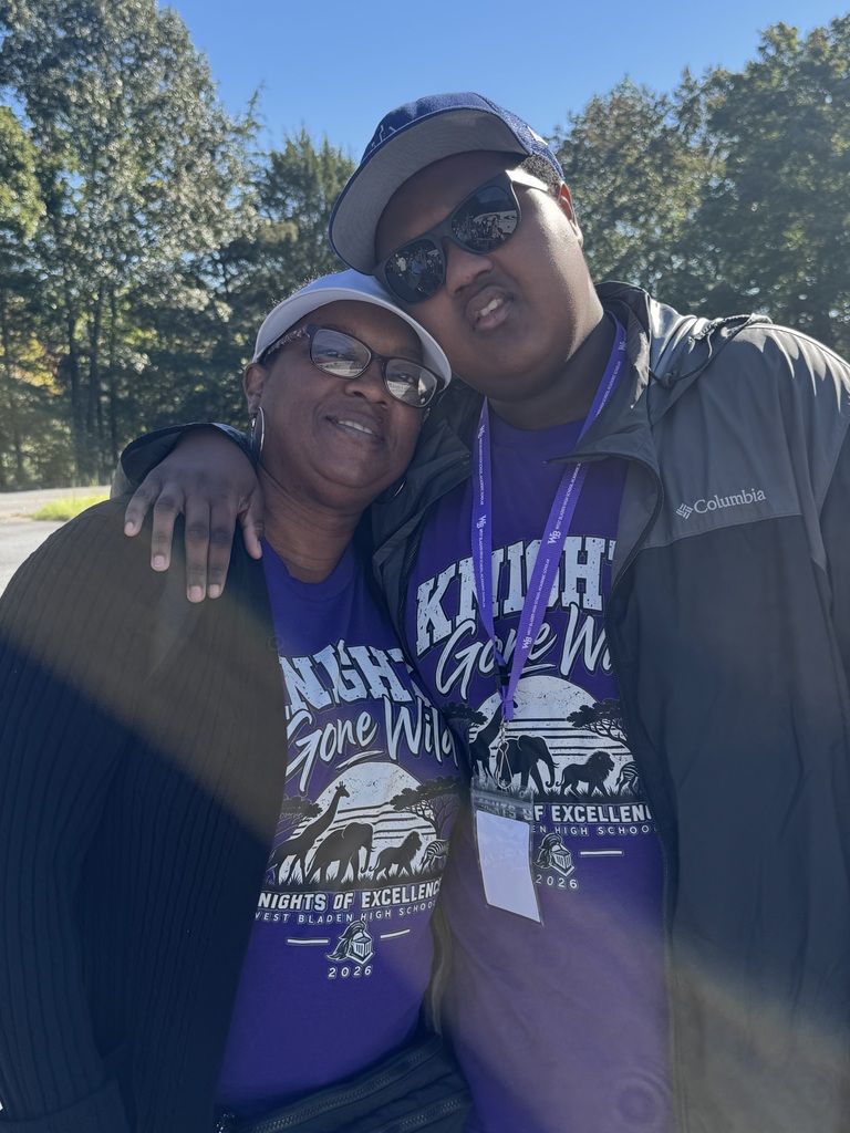 Stundent and mom posing outside of zoo in purple shirts