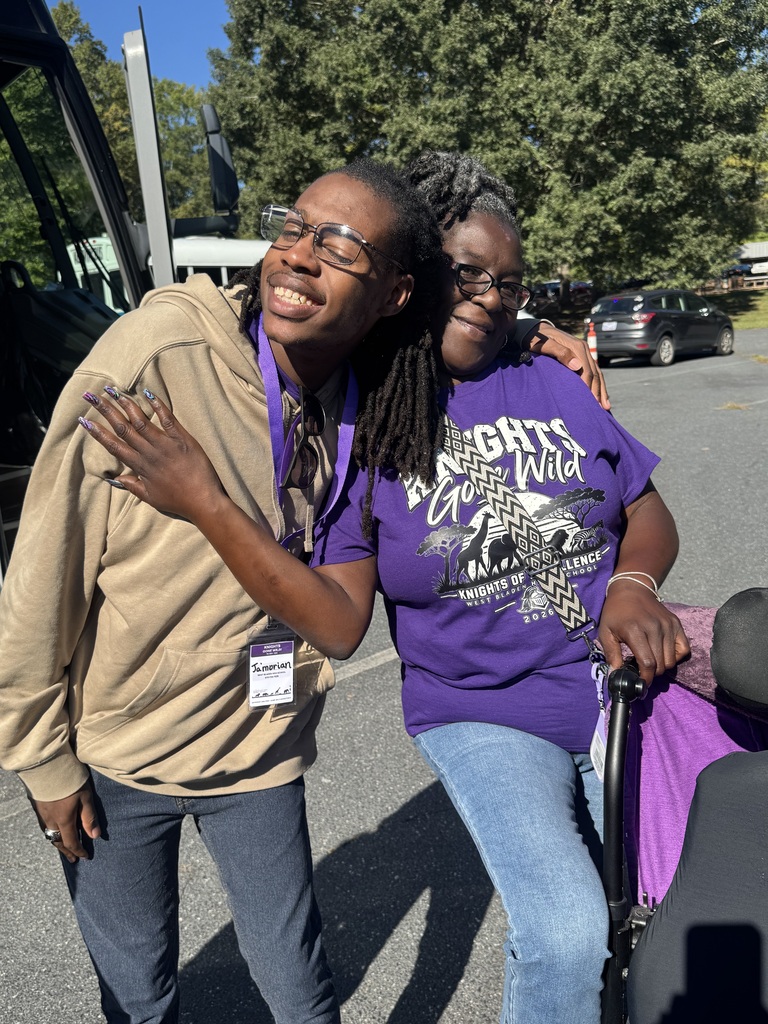 Student and teacher in purple shirts smiling as they walk around the NC zoo in Asheboro