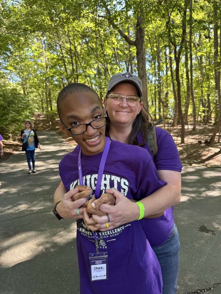 Student and assistant in purple shirts looking at the animals at the zoo