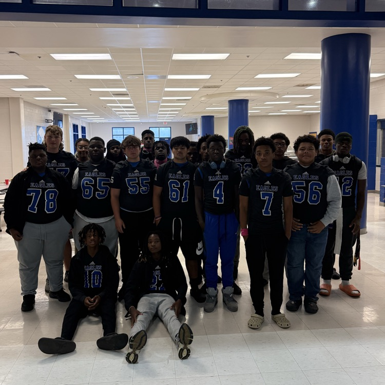 group of football players sitting and standing in front of a cafeteria