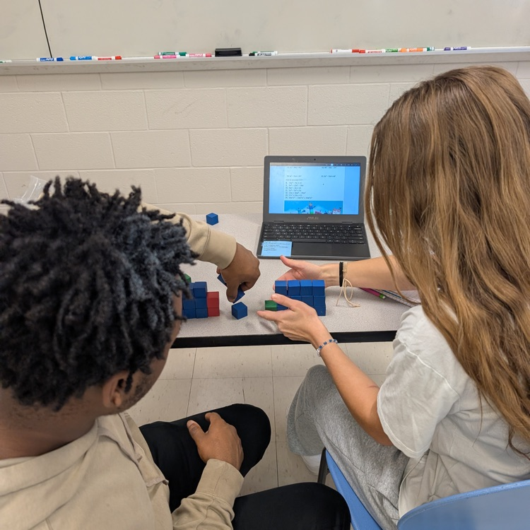 students working with red blue and green blocks at their tables with laptops