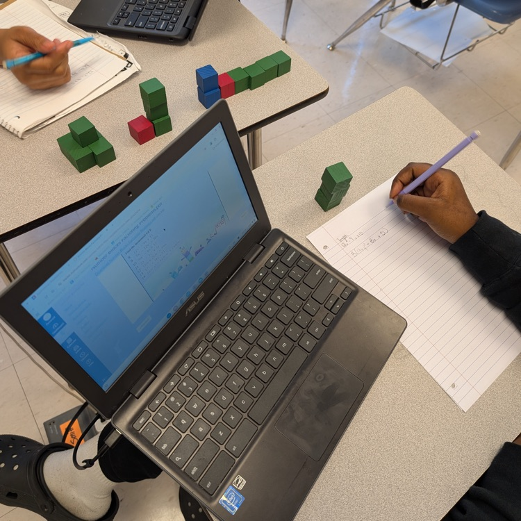 students working with red blue and green blocks at their tables with laptops