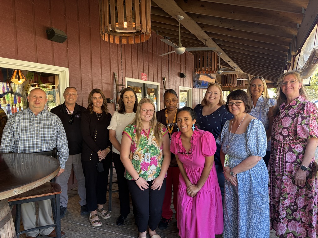 A group of educators stand smiling with Superintendent Dr. Jason Atkinson.