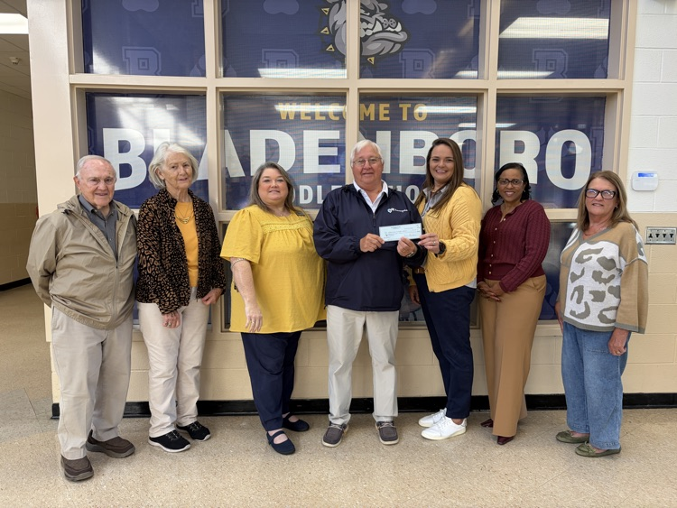 Bladenboro Rotary Club members stand smiling with Bladenboro Middle School and District Administrators .