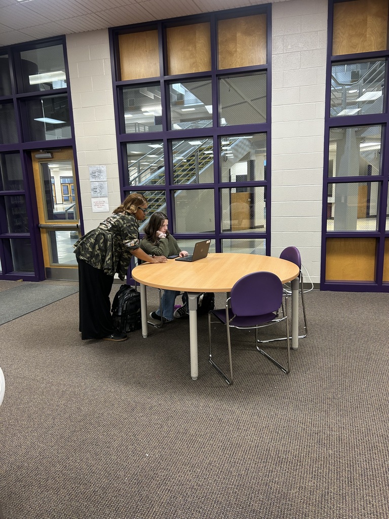 An adult assists a student working on a laptop at a table during West Bladen High School's College Application + FAFSA Workshop.