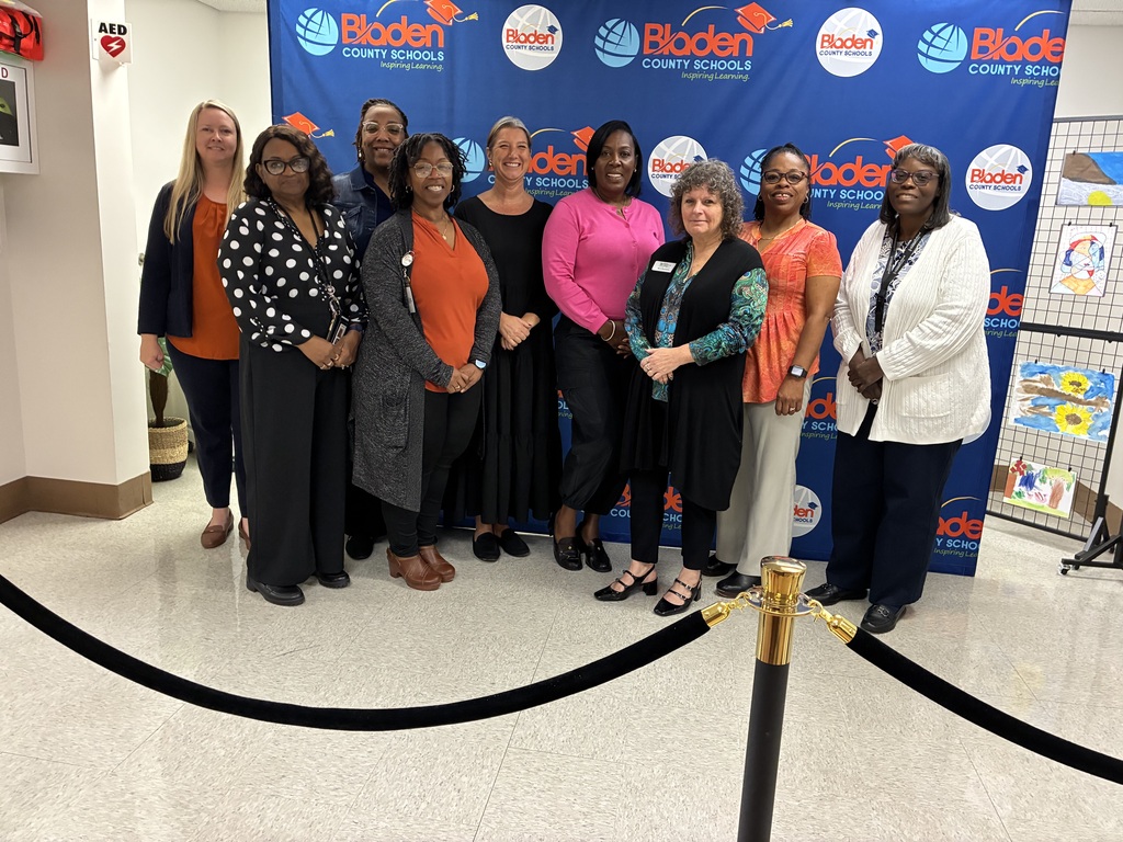 A group of professionally dressed educators stands in front of a backdrop that reads "Bladen County Schools"