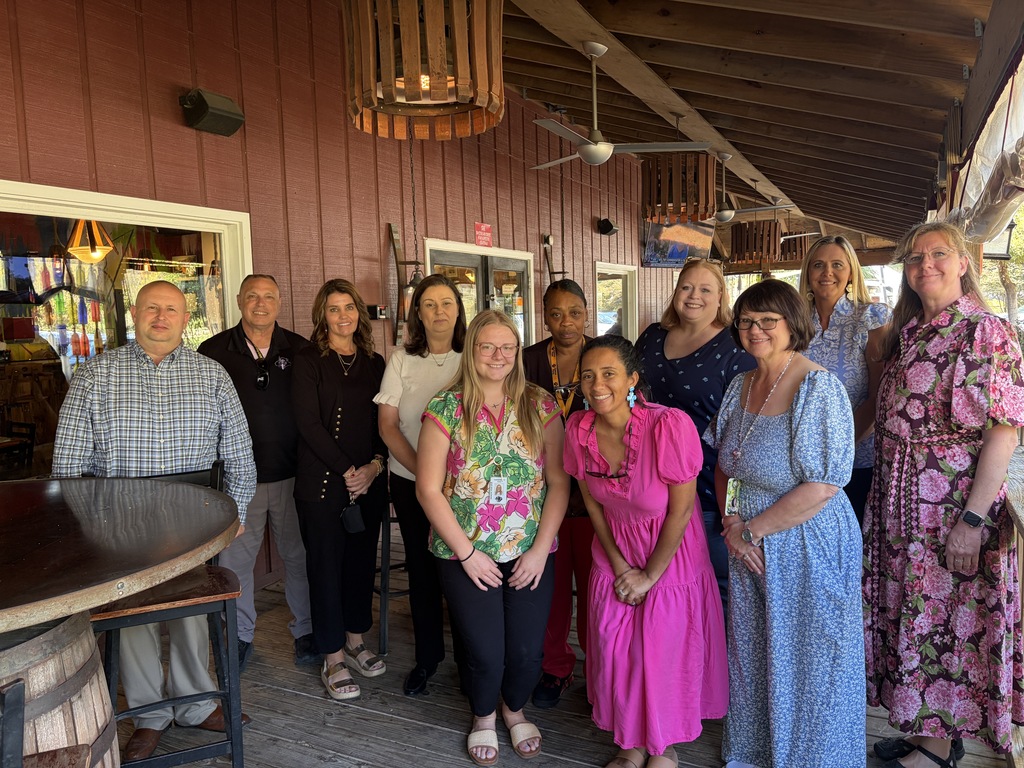 A group of educators stand smiling with Superintendent Dr. Jason Atkinson.