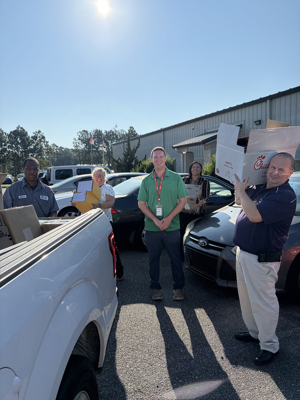 A group of adults loading school supplies in the back of a pickup truck.