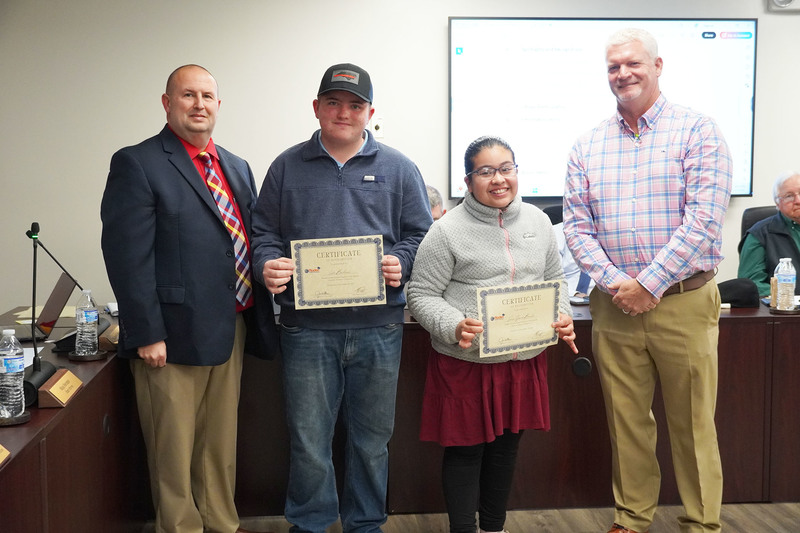 Two students hold certificates during a recognition with Bladen County Schools administrators.