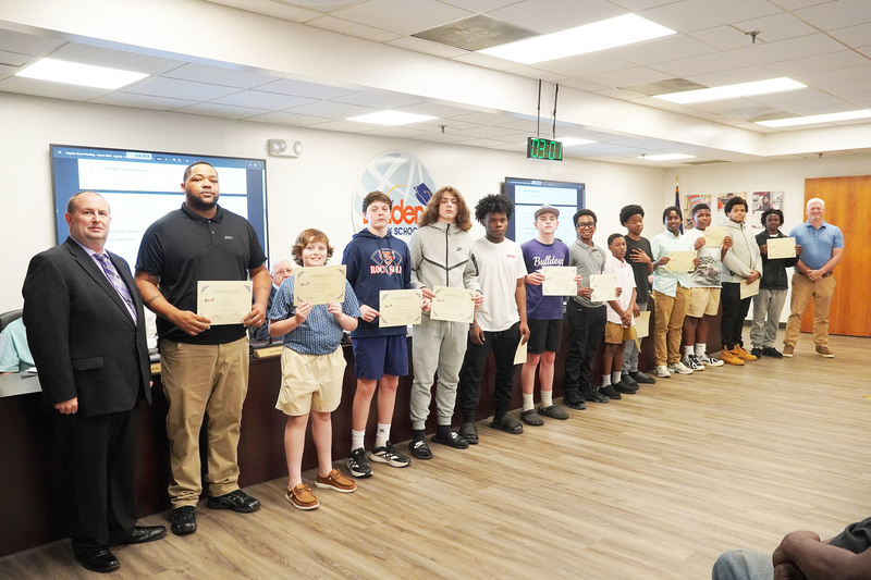middle school boys standing with superintendent, coaches and board chair