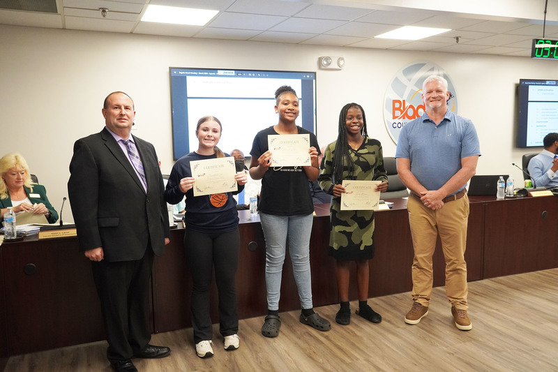middle school girls standing with superintendent and board chari