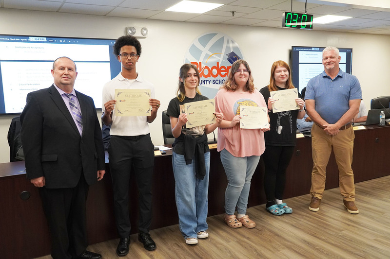 high school students hold certificates standing between two administrators