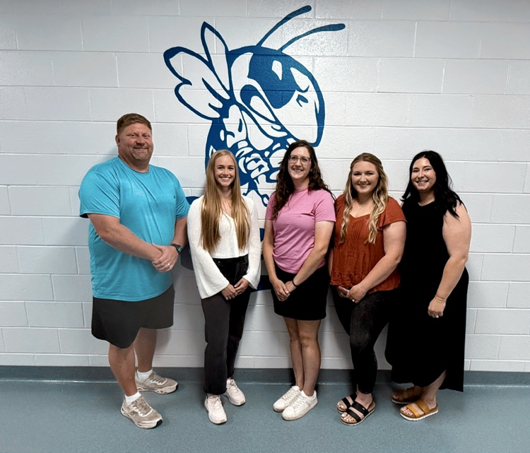 employees standing in front of the bee graphic